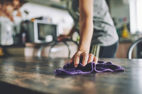 A Person Using A Purple Cloth To Clean A Kitchen Table